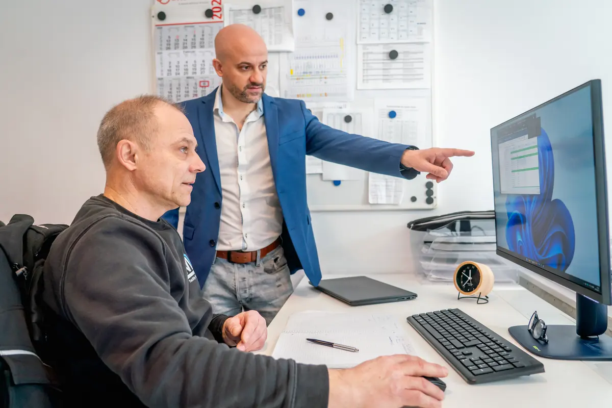 Technische Dokumentation: Mitarbeiter von ML Facility zeigt einem Kollegen etwas am Bildschirm