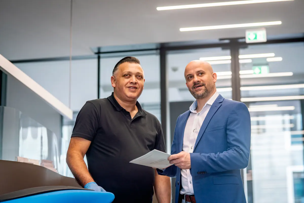 Reinigungskraft und Ansprechpartner von ML Facility besprechen ein Dokument