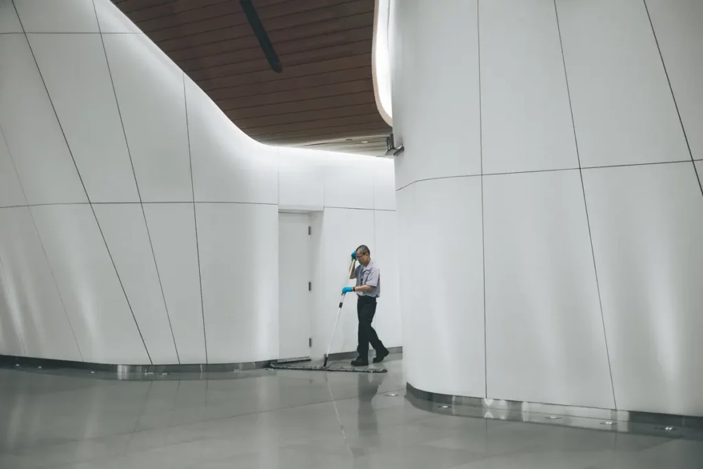 Reinigungskraft wischt den Boden einer hellen, modernen Lobby