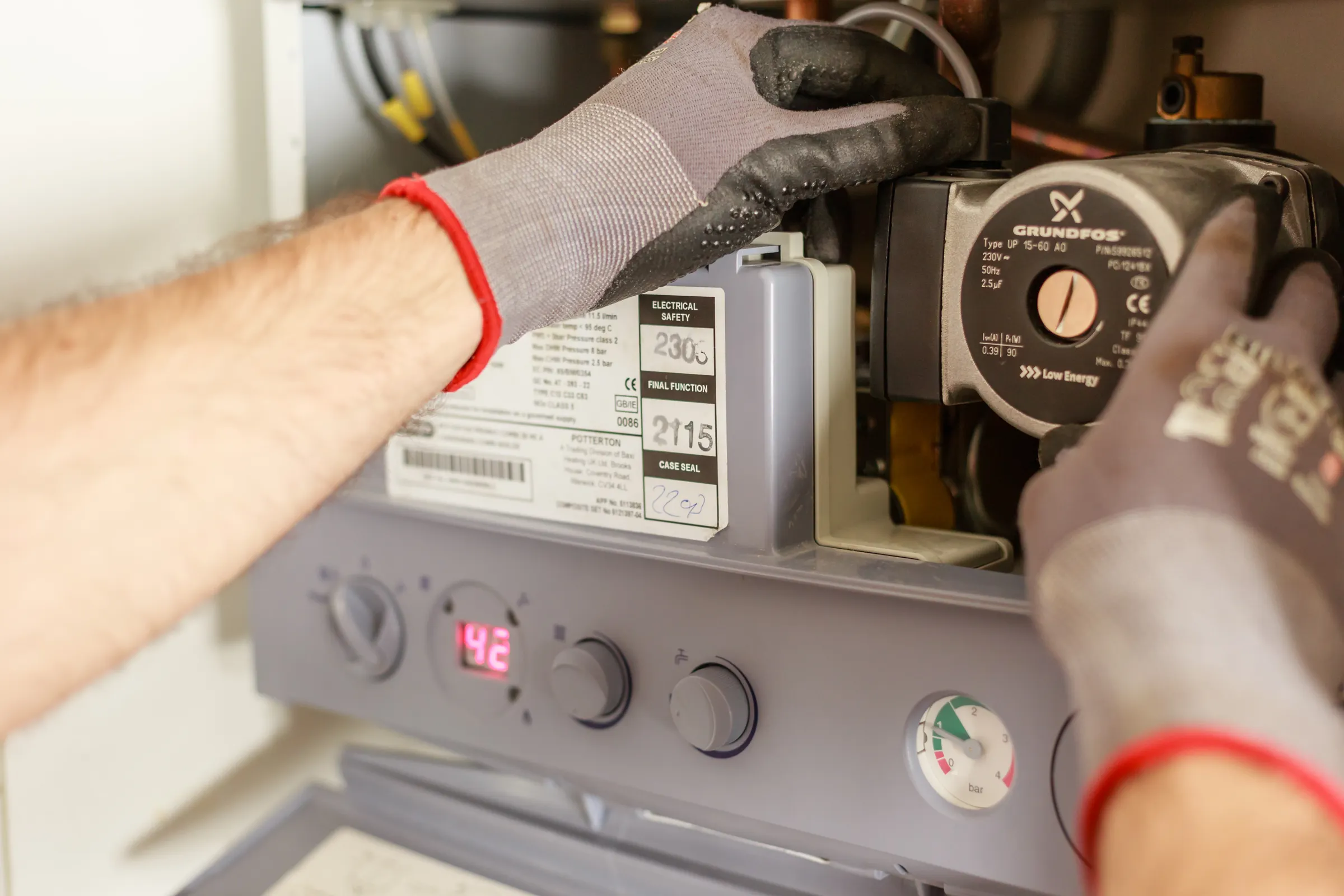 Wartung und Instandhaltung: Techniker mit Arbeitshandschuhen wartet eine Heizungsanlage an der Umwälzpumpe