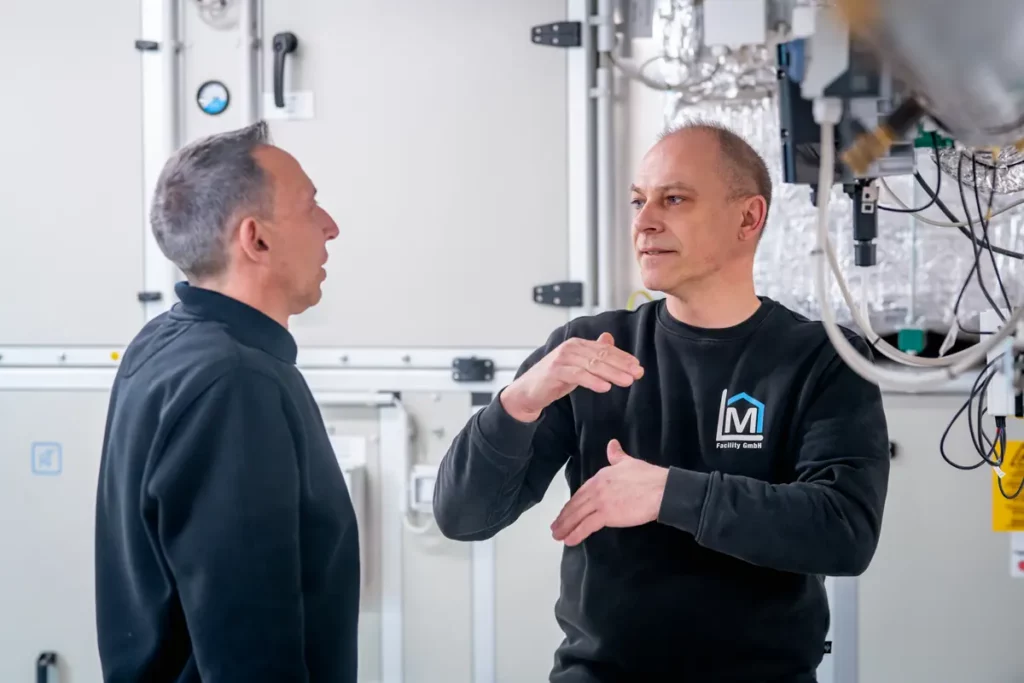 Techniker von ML Facility im Gespräch an einer Lüftungsanlage