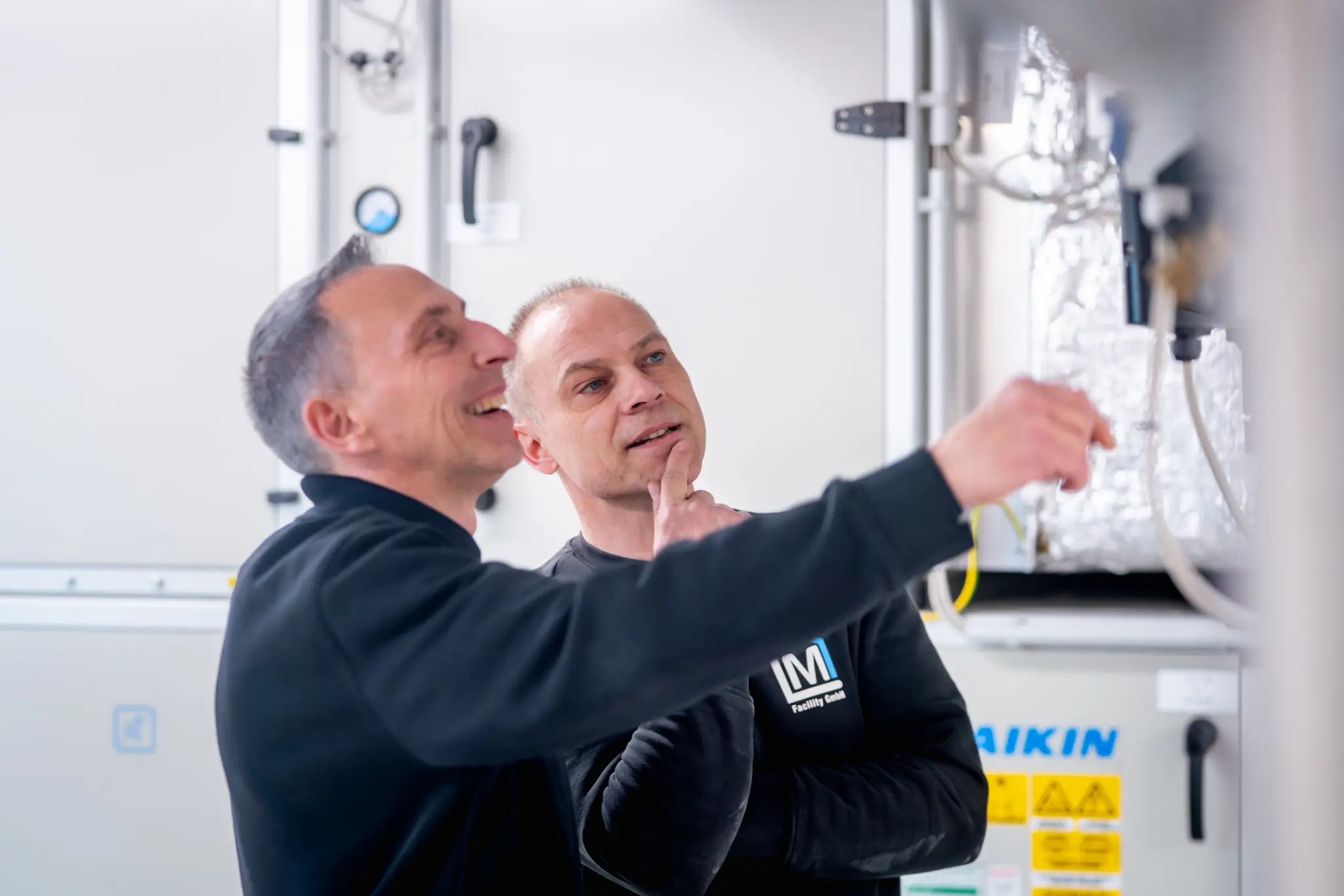 Infrastrukturelles Facility Management: zwei Techniker von ML Facility an einer Lüftungsanlage im Technikraum